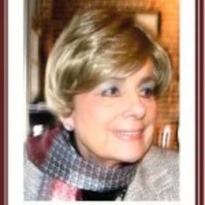 Portrait of a smiling woman with short blonde hair and a scarf.